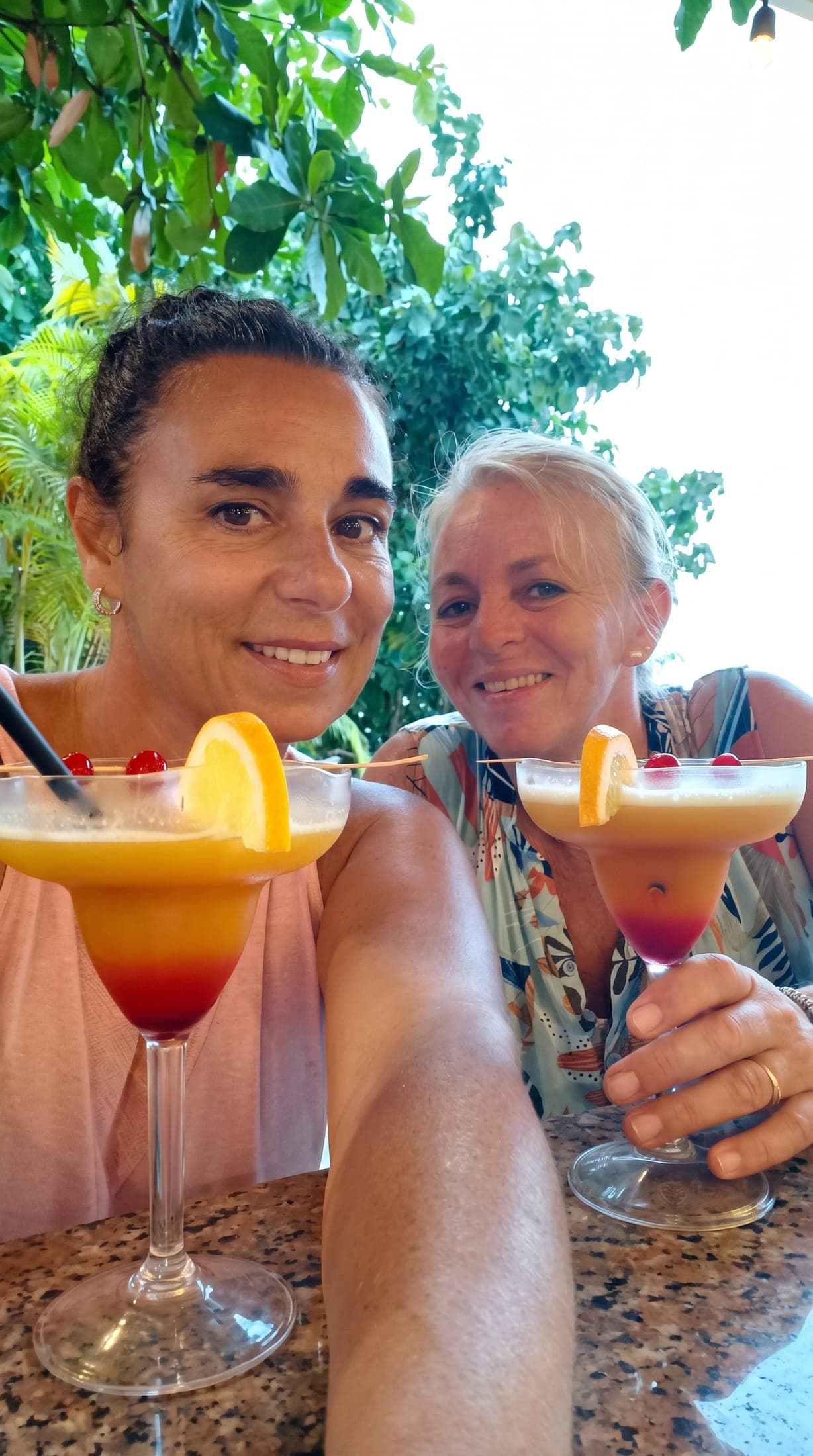 Two guests smiling with tropical cocktails on a Ziblo day out